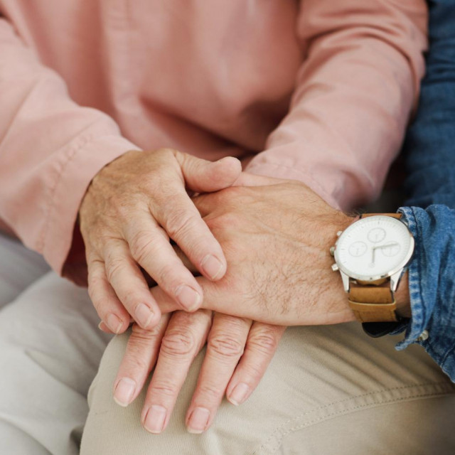 Close up of Caucasian male and female hands holding and caressing. Motherhood love. Senior mother and adult son supporting each other and hugging. Old woman and young man.