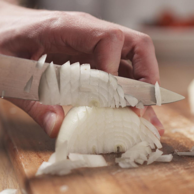 man cutting white onion with knife, wide photo