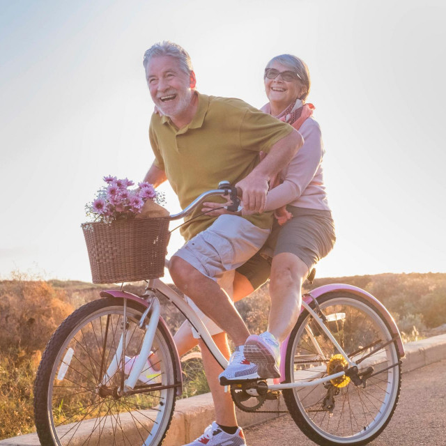 joy and happiness for adult married couple start and have fun traveling on the same bike in outdoor activity with sun backlight on the background. clear and bright image for smile and laugh people.