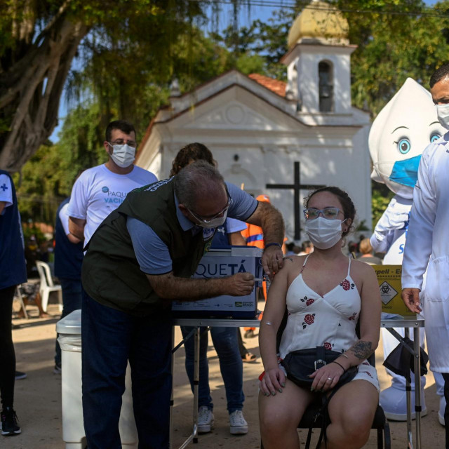 Brazil's Health Minister Marcelo Queiroga (L) gives a dose of AstraZeneca/Oxford vaccine against Covid-19 during the first day of a mass vaccination campaign within the 'Paqueta Vaccinated' project, at Paqueta island in Rio de Janeiro, Brazil on June 20, 2021. - Rio de Janeiro Municipal Health Department, with the support of the Oswaldo Cruz Foundation (Fiocruz), is carrying out the project in the island to evaluate the effects of immunization on a large scale. (Photo by Andre Borges/AFP)