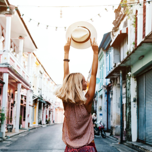 Boho girl walking on the city street. Travelling in Phuket Old Town in Thailand.