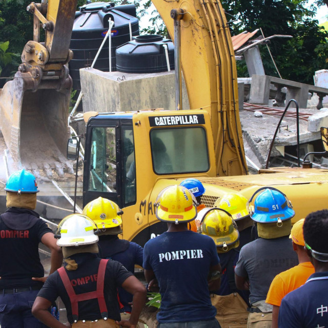 Rescue workers search through destroyed buildings in Les Cayes on August 15, 2021, after a 7.2-magnitude earthquake struck the southwest peninsula of the country. - Hunched on benches, curled up in chairs or even lying the floor, those injured in the powerful earthquake that wreaked havoc on Haiti on Saturday crowded an overburdened hospital near the epicenter. The emergency room in Les Cayes, in southwestern Haiti, which was devastated by the 7.2-magnitude quake on Saturday morning that killed at least 724 people, is expecting reinforcements to help treat some of the thousands of injured. (Photo by Stanley LOUIS/AFP)