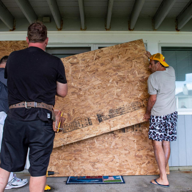 Građevinski radnici osiguravaju kuće na obali uoči dolaska uragana Henri