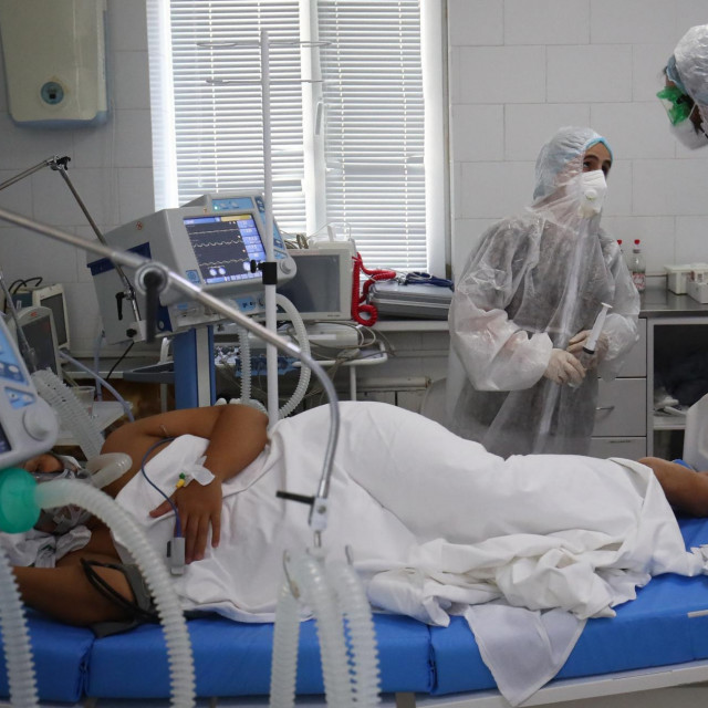 Medicinski radnici koji nose zaštitnu opremu liječe pacijenta