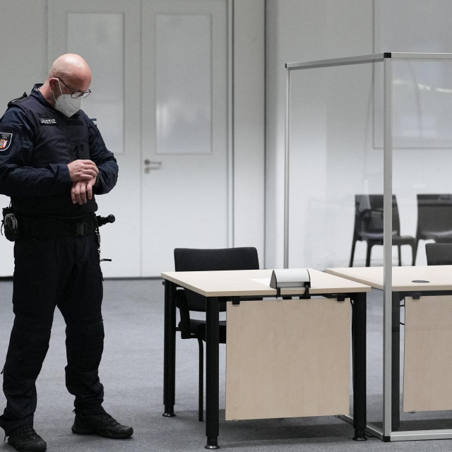 Službenik suda gleda na sat u sudnici prije suđenja 96-godišnjoj bivšoj tajnici
