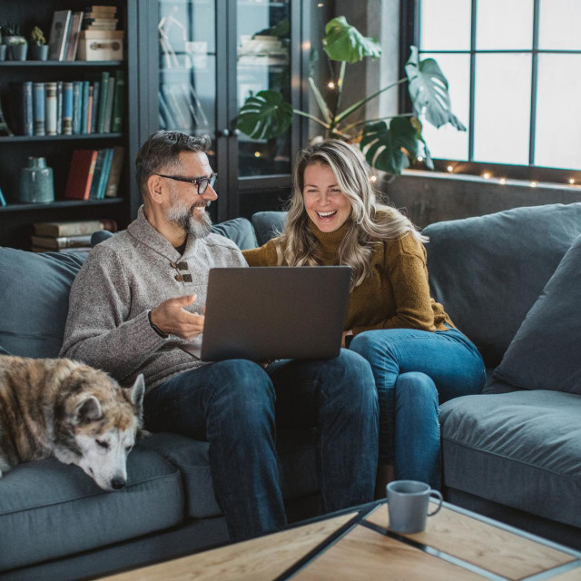 Mature couple at home using video call to talk with friends or family during pandemic isolation period.