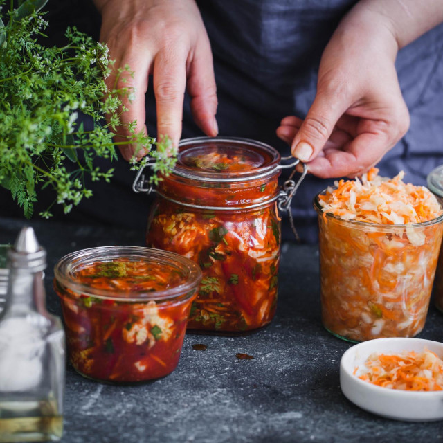 Fermented preserved vegetables food concept. Cabbage kimchi and sauerkraut sour cabbage glass jars, over rustic blue table.