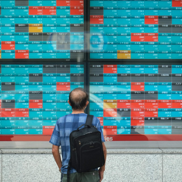 A pedestrian looks at an electronic quotation board displaying compnaies' stock prices of the Tokyo Stock Exchange in Tokyo on October 5, 2021. (Photo by Kazuhiro NOGI/AFP)