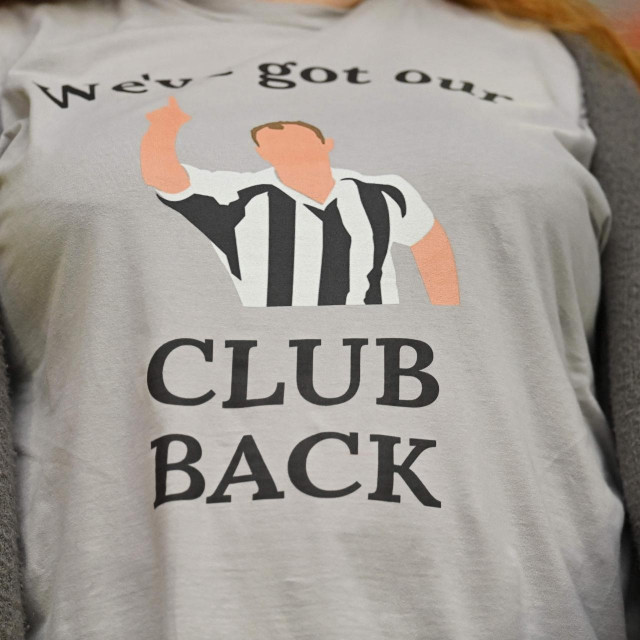 A fan wears a T-shirt celebrating the recent take over of Newcastle United by a Saudi-led consortium during the English Premier League football match between Newcastle United and Tottenham Hotspur at St James' Park in Newcastle-upon-Tyne, north east England on October 17, 2021. (Photo by Paul ELLIS/AFP)/RESTRICTED TO EDITORIAL USE. No use with unauthorized audio, video, data, fixture lists, club/league logos or 'live' services. Online in-match use limited to 120 images. An additional 40 images may be used in extra time. No video emulation. Social media in-match use limited to 120 images. An additional 40 images may be used in extra time. No use in betting publications, games or single club/league/player publications./