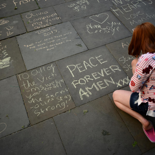 Žena gleda poruke ispisane na pločniku u centru Manchestera 22. svibnja 2018., na obljetnicu godine dana od smrtonosnog napada na Manchester Arenu