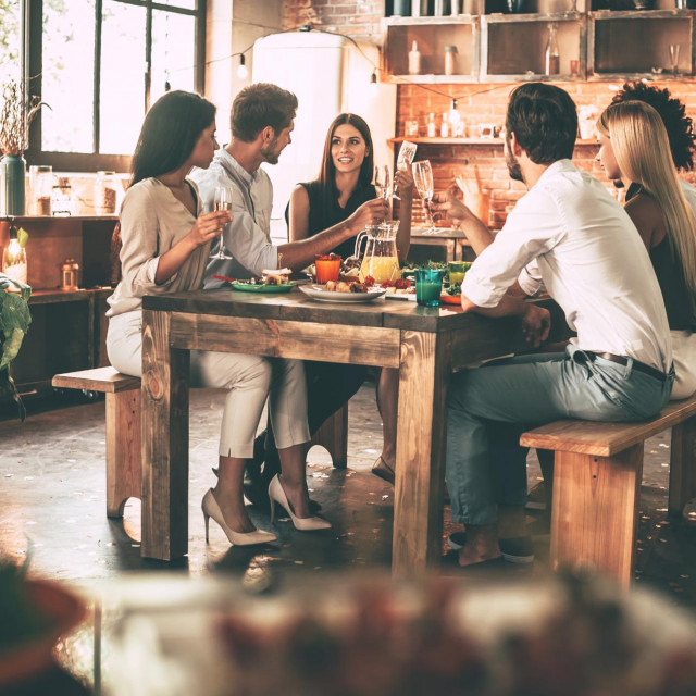 Enjoying dinner with friends. Group of cheerful young people enjoying dinner while sitting on the kitchen together