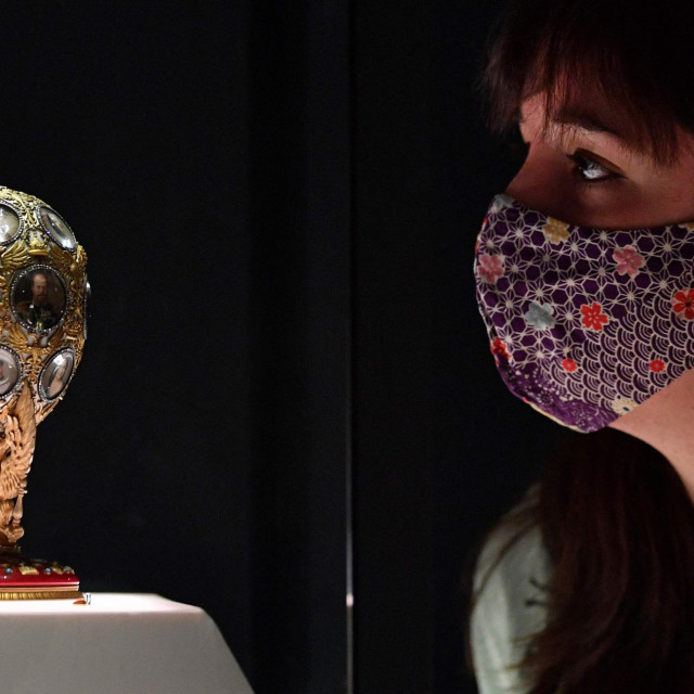 A gallery assistant poses with the 'Romanov Tercentenary Egg' during a photocall to preview the exhibition 'Faberge in London: Romance to Revolution', at the V&A (Victoria and Albert) museum in London on November 17, 2021. - The exhibition is set to open on november 20, and run until May 8, 2022. (Photo by JUSTIN TALLIS/AFP)
