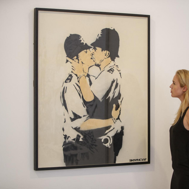 Galerijska asistentica pozira ispred ”Policajaca koji se ljube”, djela umjetnika Banksyja u galeriji Lazinc u Londonu 1
