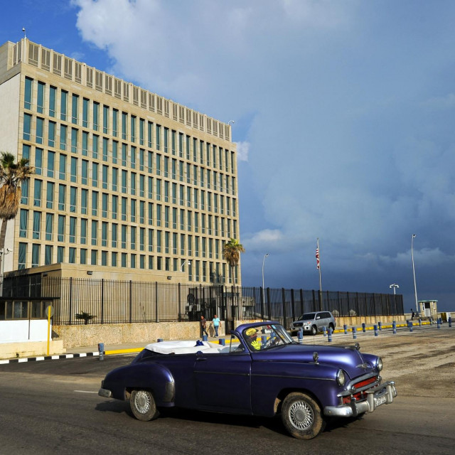 Stari automobil prolazi pored američke ambasade u Havani na Kubi
