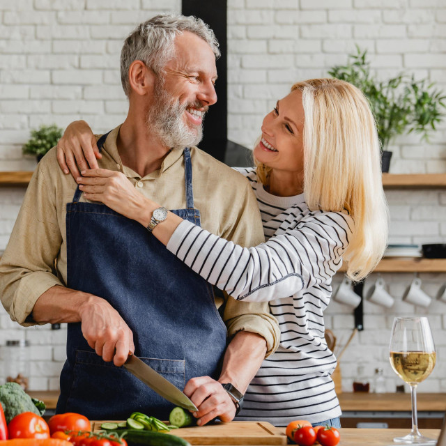 Happy senior couple cooking food with healthy fresh vegetables on kitchen at home. Concept of healthy eating