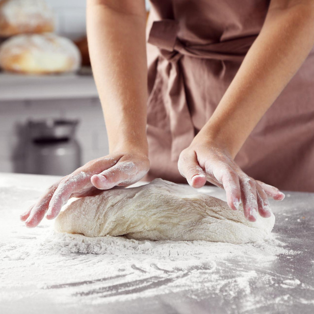 Making dough by female hands at bakery