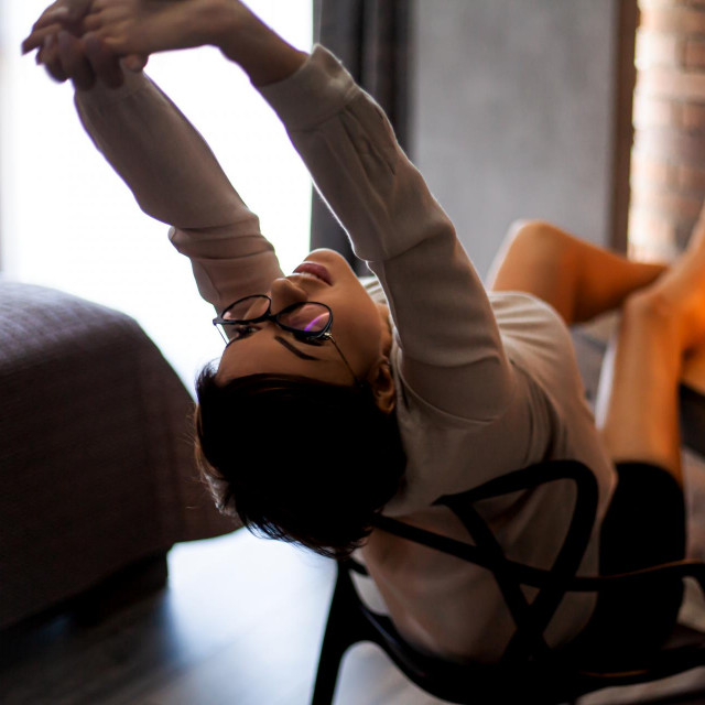 45s years old business woman working at home, sitting at a table with laptop in the evening, take the job at freelance. Entrepreneur relax after do work and doing streching.