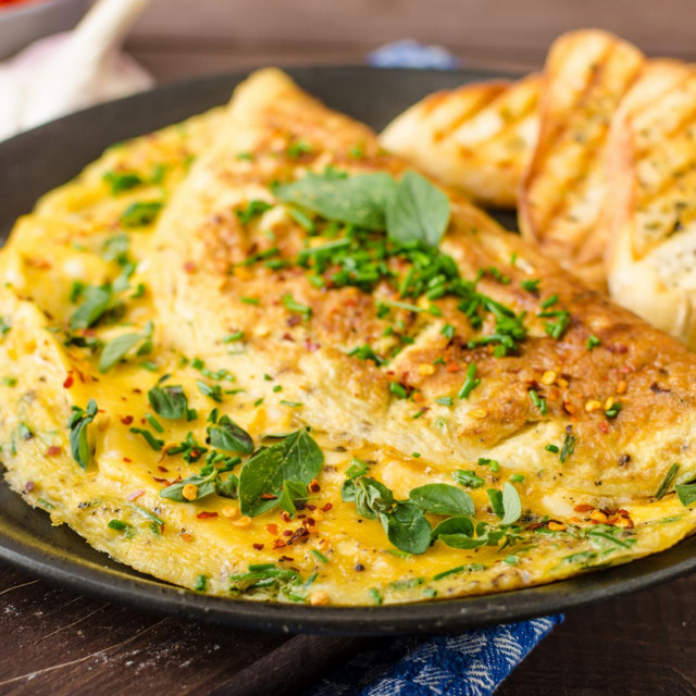 Herb omelette with chives and oregano sprinkled with chili flakes, garlic panini toasts