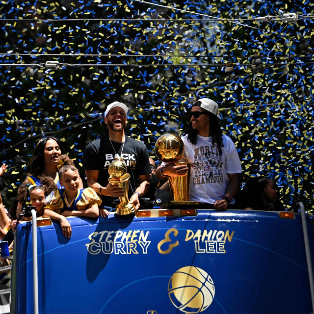 TOPSHOT - US basketball player Stephen Curry (L) holds the MVP trophy alongside teammate Damion Lee (R) as they celebrate from a double decker bus during the Golden State Warriors NBA Championship victory parade along Market Street in San Francisco, California on June 20, 2022. (Photo by Patrick T. FALLON/AFP)