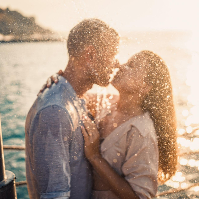 Beautiful couple in love hugs and kisses under the streams of water in a luxury spa hotel on their honeymoon, vacation in the tropics. Selective focus