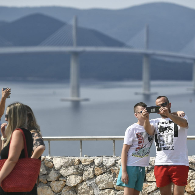 Turisti se fotografiraju uz most