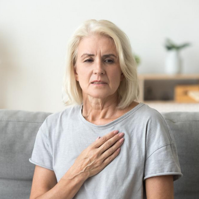 Upset stressed mature middle aged woman feeling pain ache touching chest having heart attack, sad worried senior older lady suffers from heartache at home, infarction or female heart disease concept