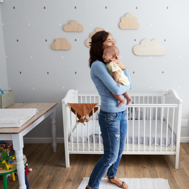 Mother Comforting Newborn Baby Son In Nursery
