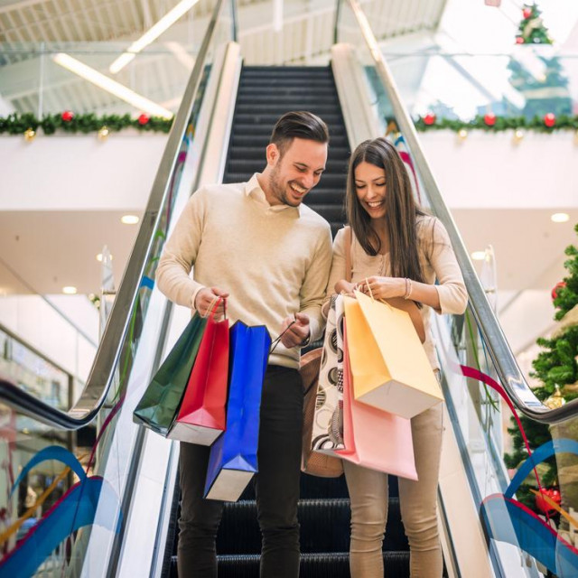 Romantic Christmas shopping.Sale, technology and people concept - happy young couple with shopping bags.Image taken inside a shopping mall.Selective focus