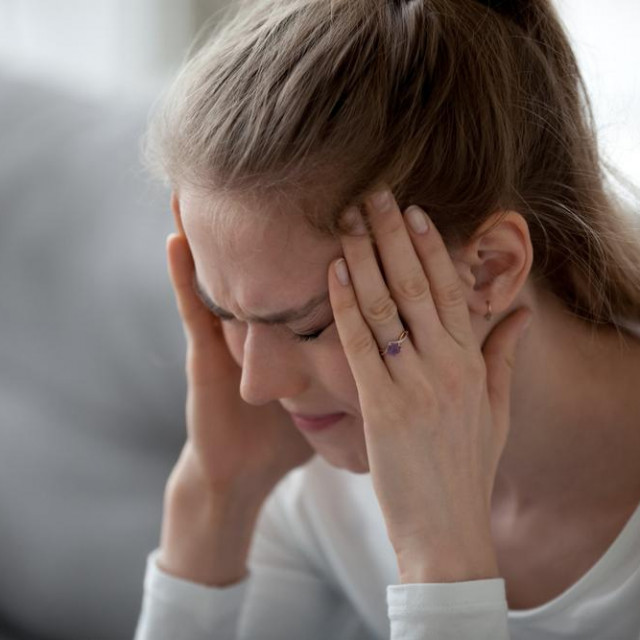 Stressed young sick woman having strong terrible headache suffering from chronic migraine or high blood pressure tension massaging temples to relieve head ache pain, tired exhausted girl feeling hurt