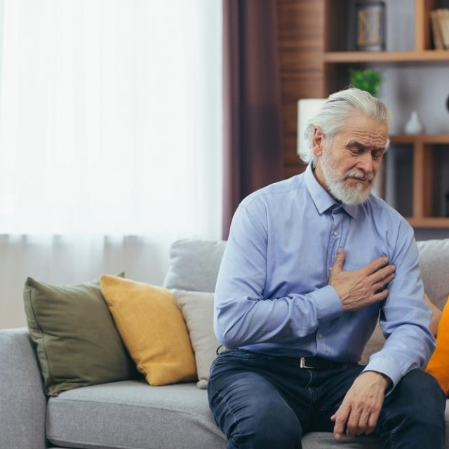 The older man sits at home alone, the grandfather holds his hands on his chest, his heart aches