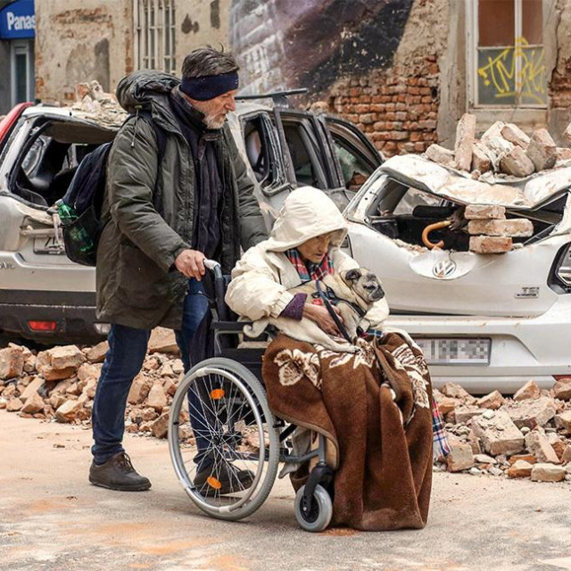 Jedan od upečatljivijih prizora snimljenih nakon potresa: gospođa u invalidskim kolicima, pognula je glavu pod kapuljačom, u naručju joj je francuski buldog