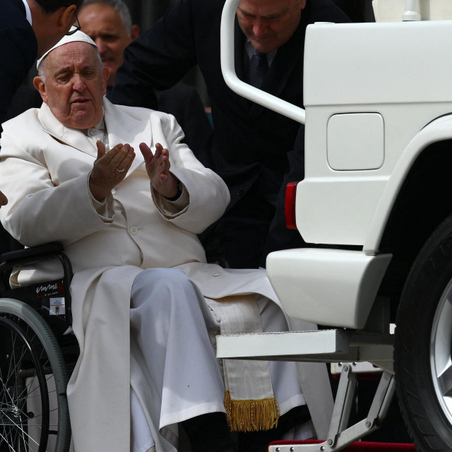 TOPSHOT - Pope Francis speaks with his aides prior to being helped get up the popemobile car from his wheelchair, as he leaves on March 29, 2023 at the end of the weekly general audience at St. Peter‘s square in The Vatican. - Pope Francis has been at the Gemelli Hospital in Rome since the afternoon of March 29, 2023 for some previously scheduled check-ups, the Holy See press director said. (Photo by Vincenzo PINTO/AFP)