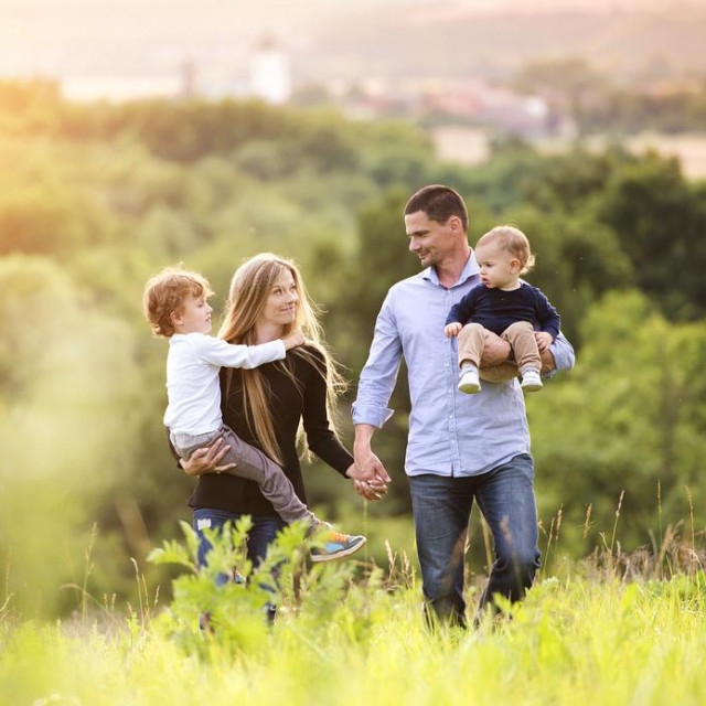 Happy young family spending time together outside in green nature.