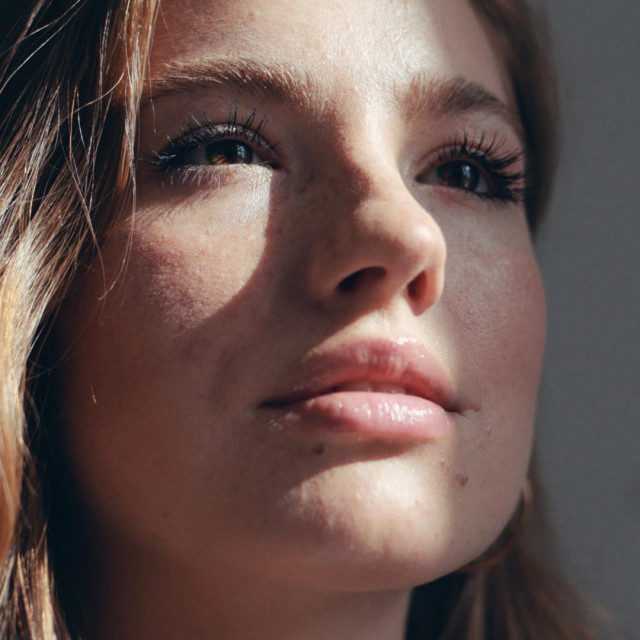 Close up portrait of pretty young woman with cute freckles looking at sun in the apartment feel happy the sun is shining