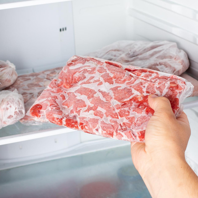 The Man takes out a bag of frozen meat from the freezer in the kitchen at home. Frozen food