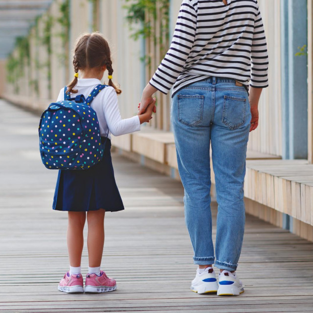 first day at school. mother leads a little child school girl in first grade