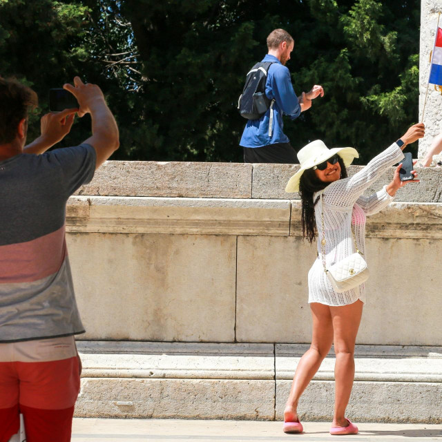 Turistkinja s hrvatskom zastavicom pozira na trgu Forum
