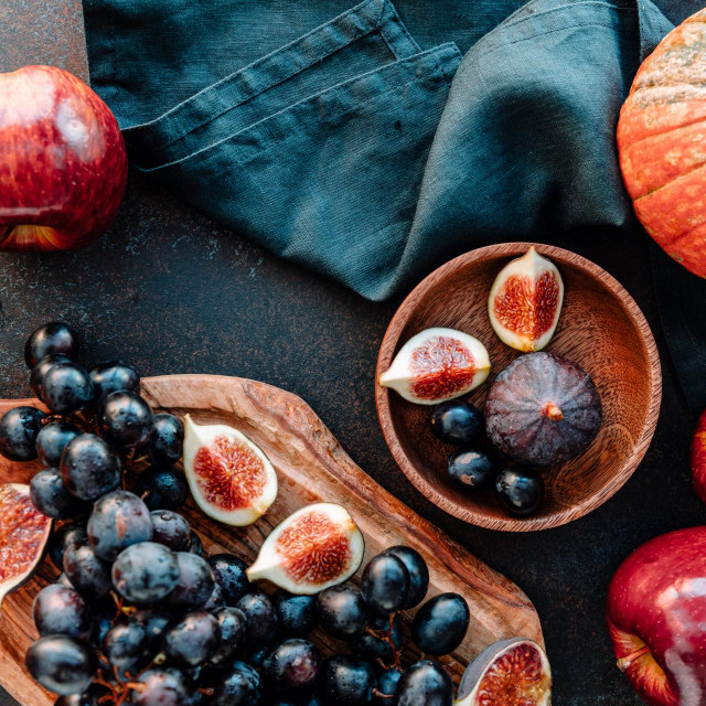 Top view of Autumn food still life with season fruits and vegetables like Bangalore blue grape, red apples, pumpkins and figs on a table.
