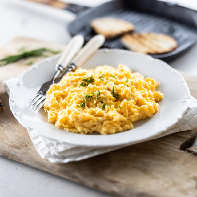 Plate of scrambled organic eggs served with bread toasted on a griddle pan.