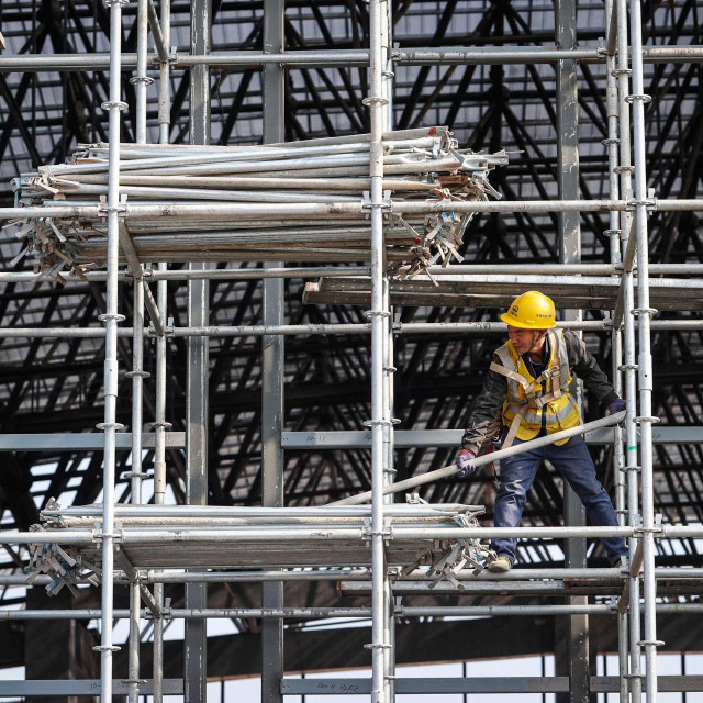 Workers are seen on scaffolding at a railway station construction site in southwestern China‘s Chongqing municipality on February 18, 2024. (Photo by AFP)/China Out