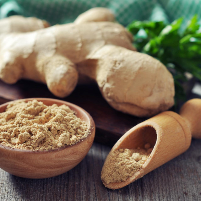 Fresh ginger root and ground ginger spice on wooden background
