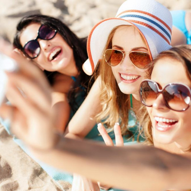 summer holidays, technology and beach concept - girls taking selfie on the beach