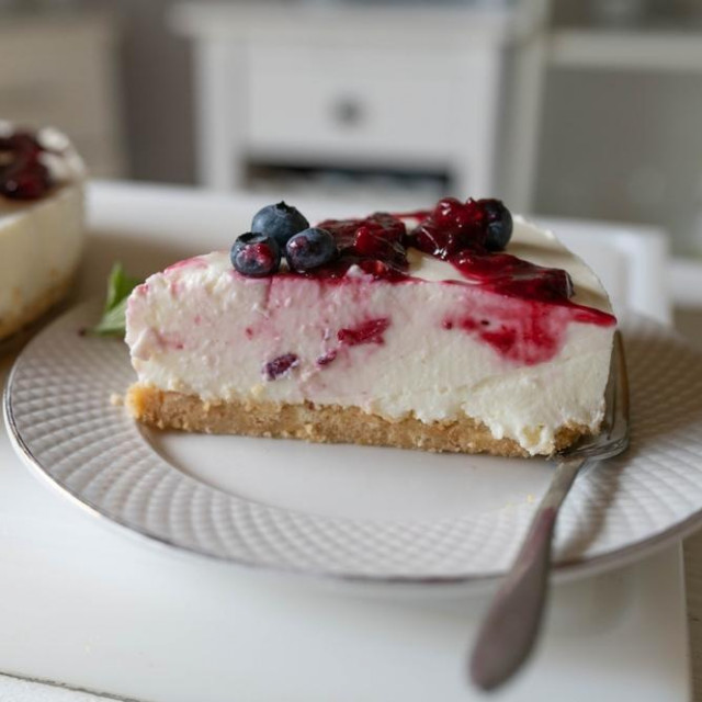 Piece of no bake cheesecake with berry topping on kitchen counter