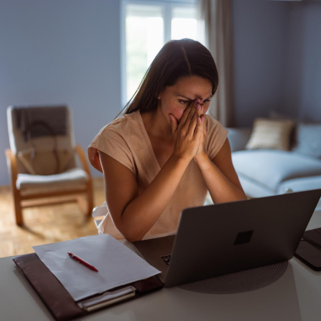 Female victim of financial fraud, looking anxious. She is at her home, discovering financial fraud
