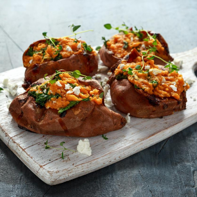 Roast sweet potato stuffed with feta cheese and kale. healthy food.