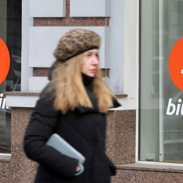 Ilustracija, žena prilazi ispred Bitcoinova izloga u Kijevu