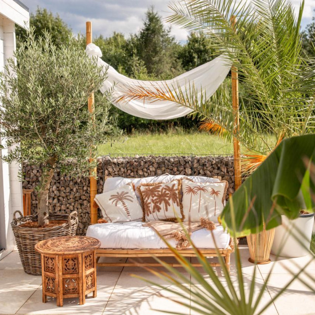 Cozy garden outdoor sofa in boho bamboo style with natural material and linen