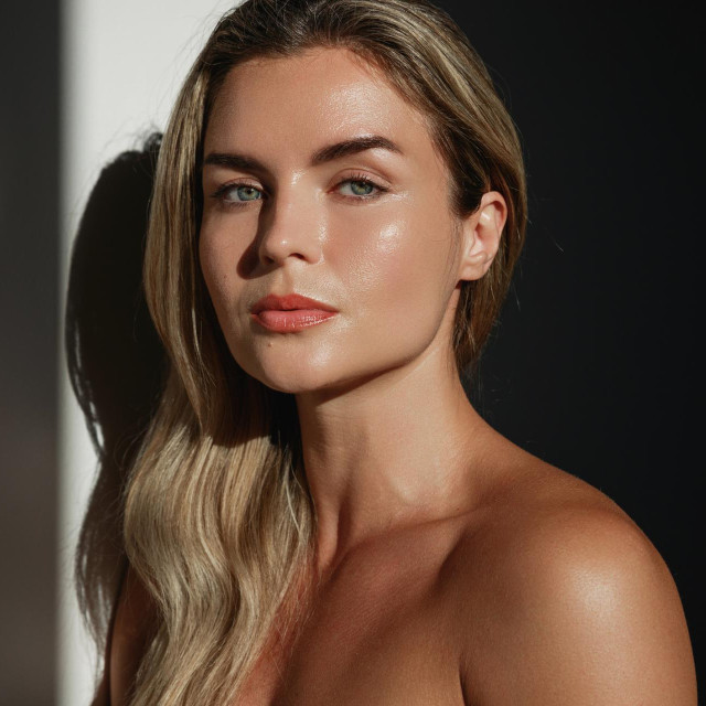 Portrait of young woman with long blonde hair in sunlight.