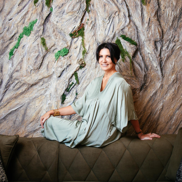 Tanja Medanić in front of the living room rock wall that looks real - it even has moss 