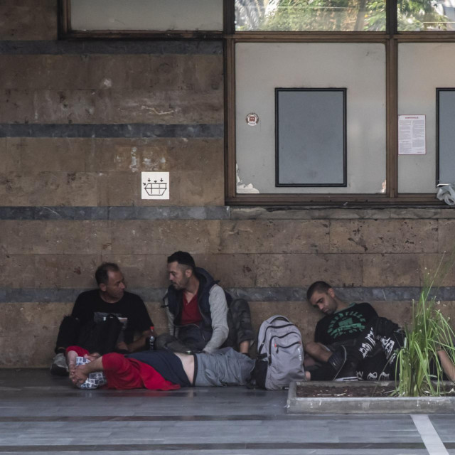 Ljudi sjede i leže na prostoru Autobusnog kolodvora Maribor